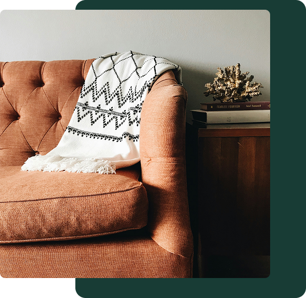 A brown/orange leather chair next to a wooden furniture.